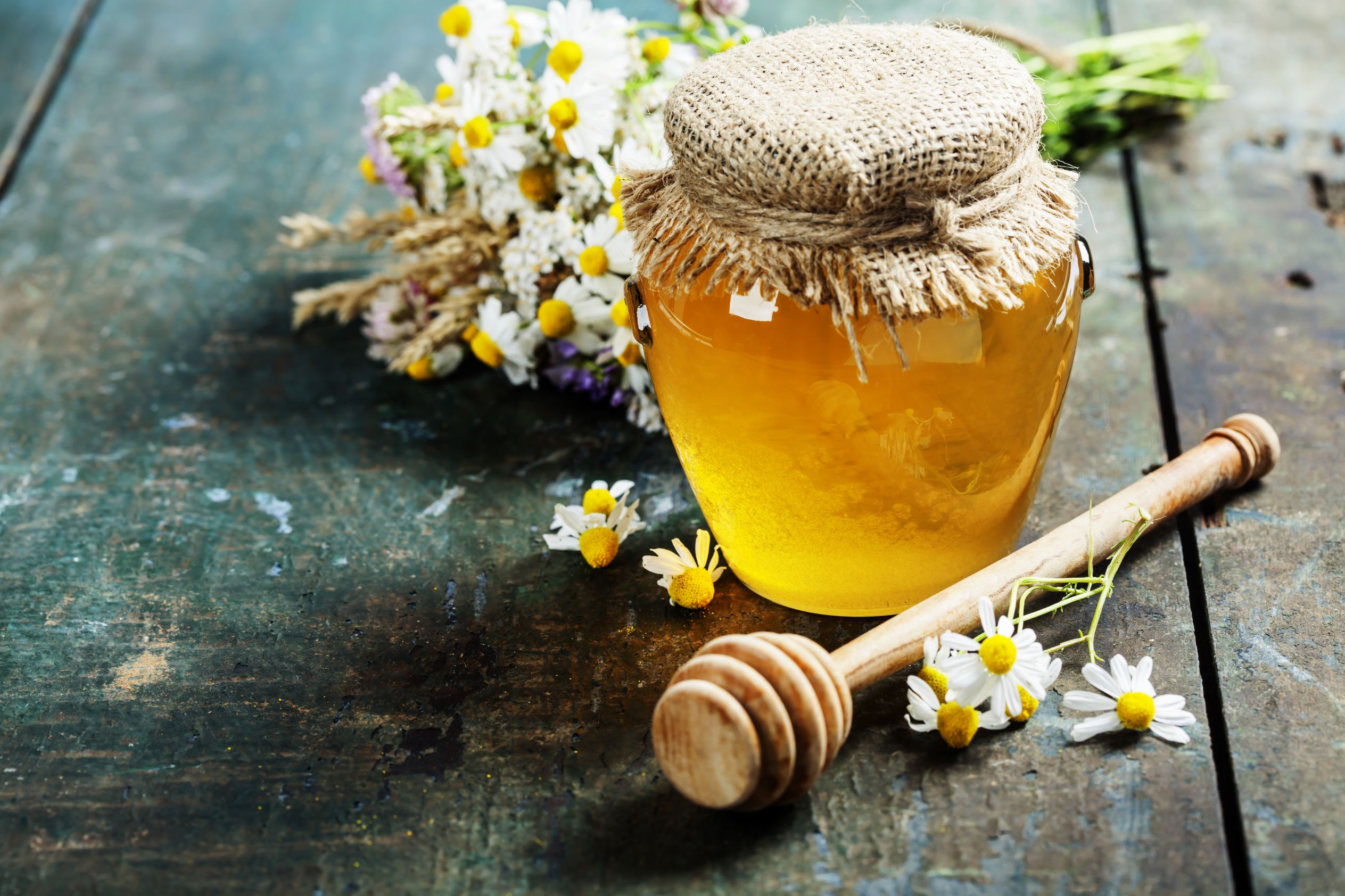 Honey jar and dipper on wooden background