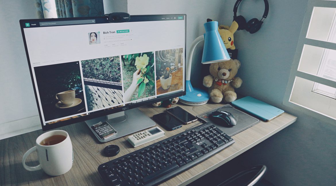 turned-on-monitor-keyboard-and-items-on-desk-1714341